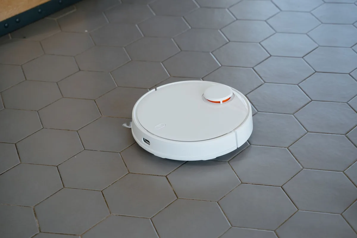Barredora robot blanca funcionando sobre piso de loseta hexagonal