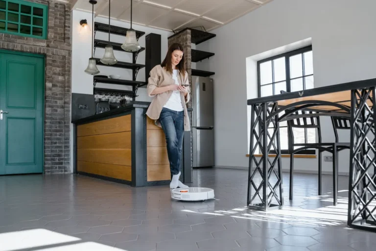 Mujer usando una aspiradora robot en una cocina moderna